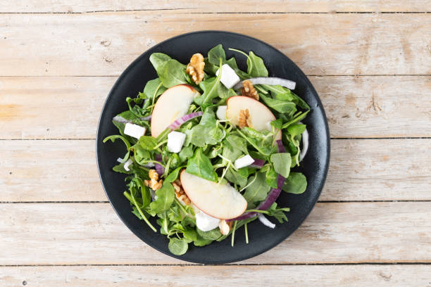 istock Autumn salad with apples and walnuts on wooden table 1566950737