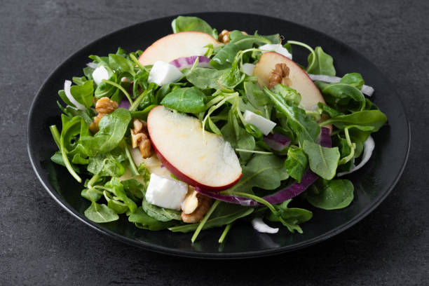 istock Autumn salad with apples and walnuts on black slate background 1566955235