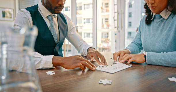istock Creative people, hands and puzzle pieces in team building for problem solving strategy at the office. Man and woman in teamwork for startup partnership, brainstorming or jigsaw solution at workplace 1566956332