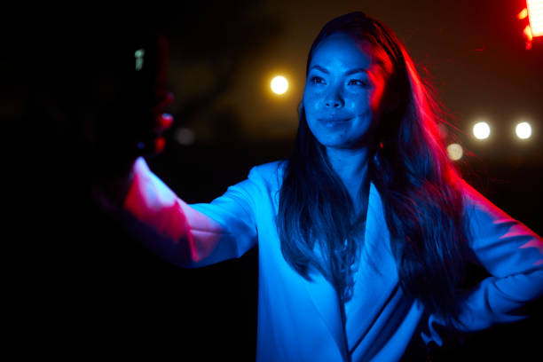 istock woman posing with red and blue lights at night 1566965556