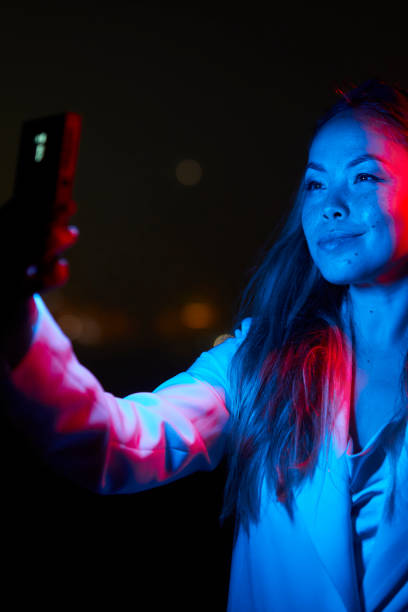 istock woman posing with red and blue lights at night 1566966629