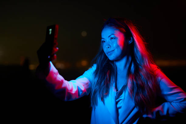 istock woman posing with red and blue lights at night 1566966746