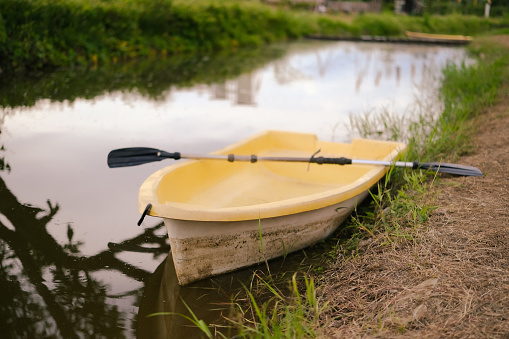 Yellow boat with paddle floating on calm water. Solitude, calmness and relaxation.