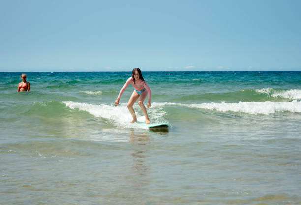istock Pretty young girl sliding on ocean waves with her surfboard 1566998511