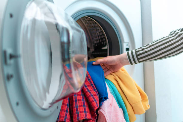 istock Loading colored clothes and linen in washing machine. Doing laundry at home 1567004944