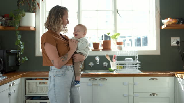 Kitchen, love and dancing mother with baby for care, support and bonding for quality time with child in a home. Infant, house and woman or mom playing with kid for fun, freedom and happiness