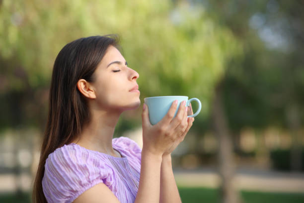 istock Woman smelling coffee from mug in a park 1567074450