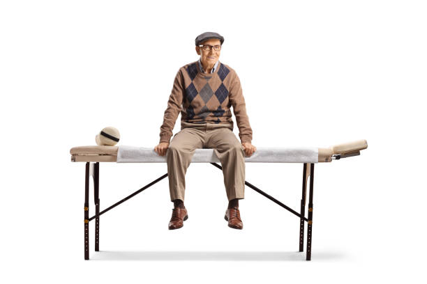istock Elderly man sitting at a physical therapy bed and smiling 1567077122