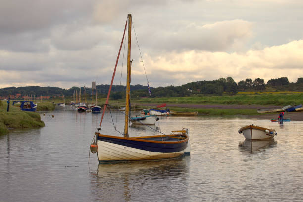 Boats floating on the creeks of the Morston Quay inlet at sunset, with Blakeney Village in the background