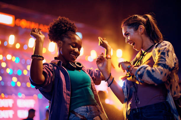 alegres amigas bailando frente al escenario de música durante el festival de verano. - concierto de música pop fotografías e imágenes de stock