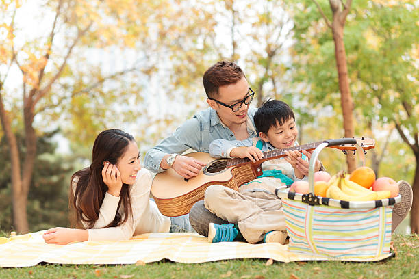 happy family playing guitar in park happy family playing guitar in park father and son guitar stock pictures, royalty-free photos & images