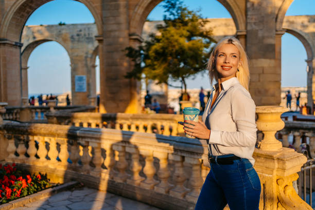 istock Young Woman Drinking Coffee And Using Phone In Valletta Malta 1567140376