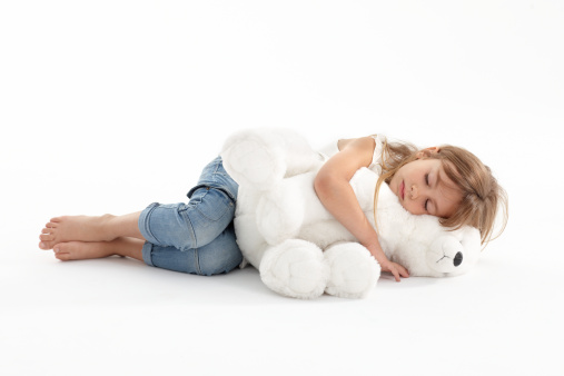 Little cute girl lying on the floor and sleeping with a big teddy bear