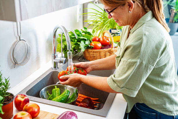 Woman washing tomatoes in kitchen sink