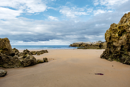 Beautiful and quiet sandy beach with sedimentary rocks outcrops in Playa Virgen del Mar, Costa Quebrada, Cantabria, North Spain