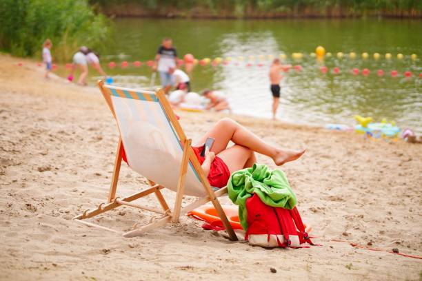 Mosina, Poland – July 23, 2023: A person lying in a comfortable lawn chair on a sunny beach
