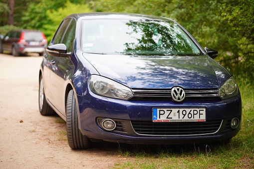 Mosina, Poland – July 23, 2023: A blue Volkswagen parked on the sands in a residential area, with lush green trees