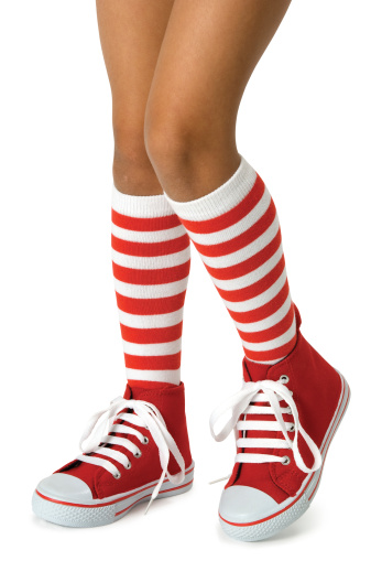 Young girls legs wearing long red striped socks with red shoes on a white background. Clipping path included.