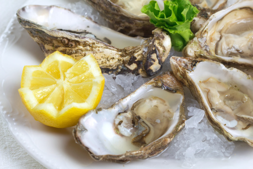 A delicious plate of freshly shucked oysters served with a wedge of lemon and fish roe, garnished with parsley