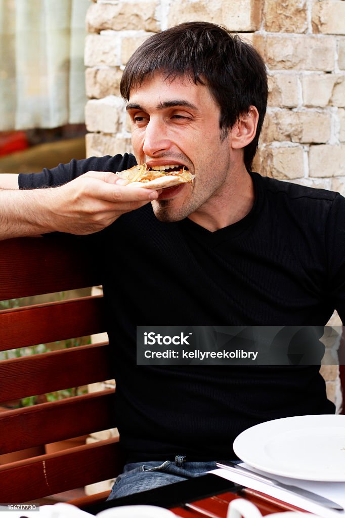 Cara está comendo pizza com um apetite - Foto de stock de Adulto royalty-free