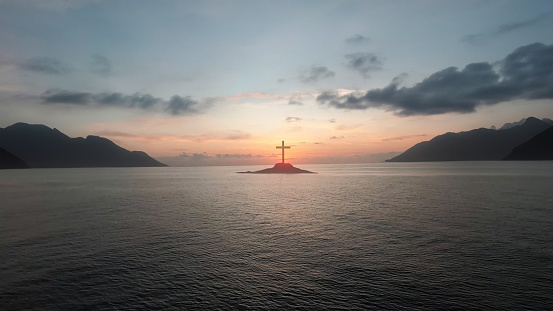 Christ Cross on an island in the middle of the open sea. Concept for faith, power, worship, christianity and easter