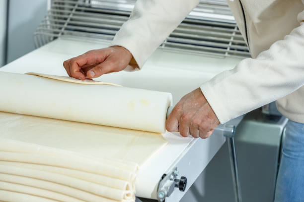 istock Rolling dough sheets with rolling pin in small business 1567185742