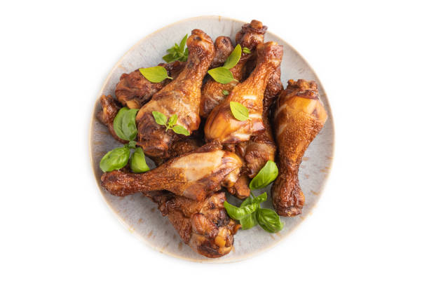 istock Smoked chicken legs on a ceramic plate isolated on white background. Top view, close up. 1567201156