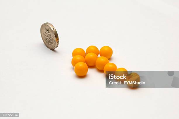 Yellow Arrow Of Pills Pointing On One Pound Coin Stock Photo - Download Image Now - Arrow Symbol, British Coin, British Currency