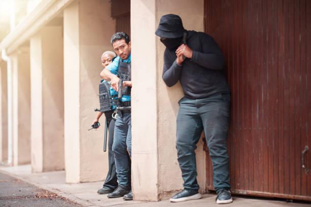Police, criminal and gun taking cover for security, backup or law enforcement outside house. Man, woman cop and dangerous robber with weapon in crime for justice, investigation or protection service la policía, el criminal y las armas se cubren para la seguridad, el respaldo o la aplicación de la ley fuera de la casa. hombre, mujer policía y ladrón peligroso con arma en el crimen para la justicia, investigación o servicio de protección