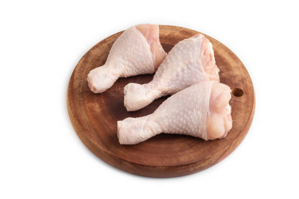 istock Raw chicken legs on a wooden cutting board isolated on white. Side view. 1567233655