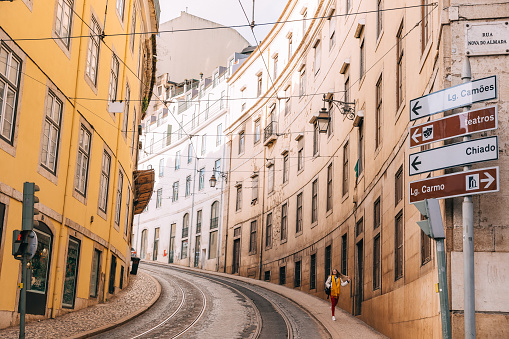 Lisbon, Portugal - 27 January, 2019 - girl walks the streets of the ancient city of Lisbon. the street with tram tracks and pavement goes up. beautiful architecture of buildings.