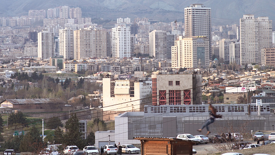 One person sliding down from a Zipline with the backdrop of the city of Tehran