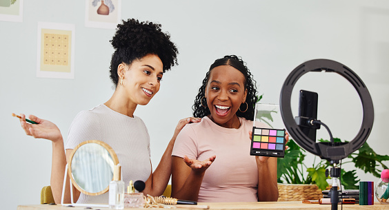 Vlogging, friends and women doing a makeup tutorial together with technology for social media, Happy, fun and young interracial female people filming a cosmetic, beauty or face routine on a phone,