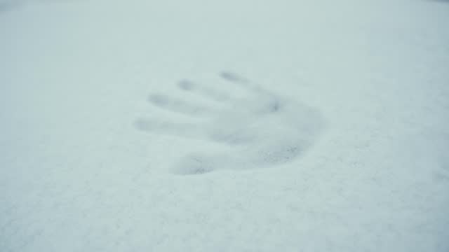 The girl leaves a handprint on the first snow.