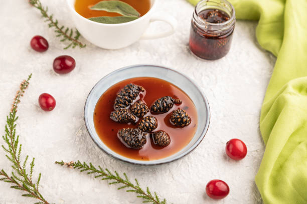 istock Pine cone jam with herbal tea on gray concrete, side view, selective focus. 1567272008