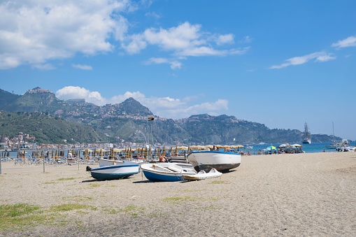 Sandy beach in Giardini Naxos, mountains with the town of Taormina in the background