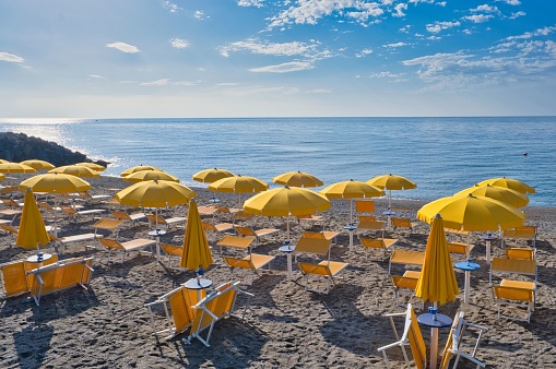 sandy beach with yellow umbrellas in Giardini Naxos, near Taormina, Sicily, Italy