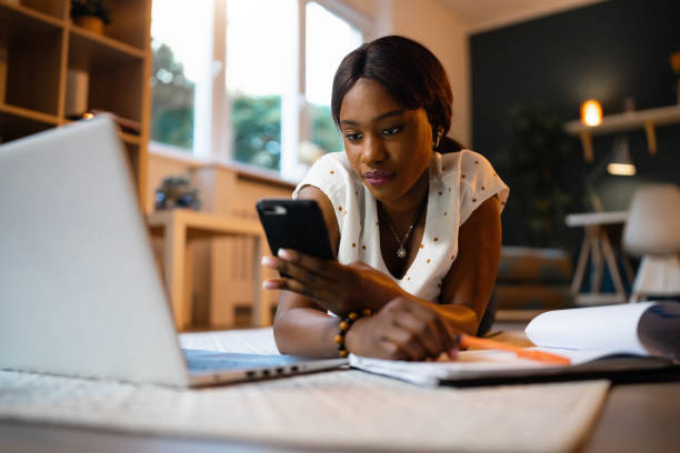 istock Young woman of Black ethnicity using mobile phone while studying 1567290772