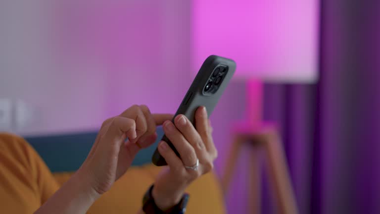 Close-up shot of female's hands using smart phone for control and change color the lights.