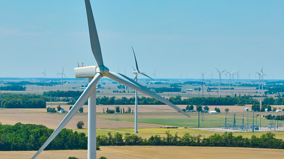 Image of Aerial close up of wind turbine with wind farm in background and substation