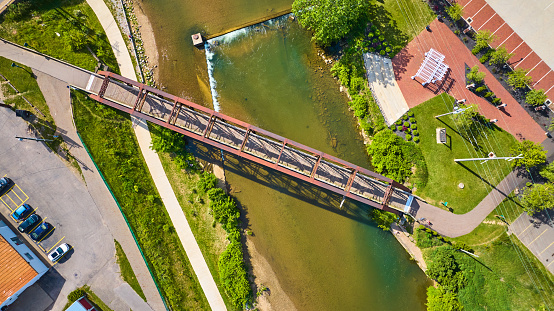 Image of Aerial downward drone shot of metal truss walking bridge and river