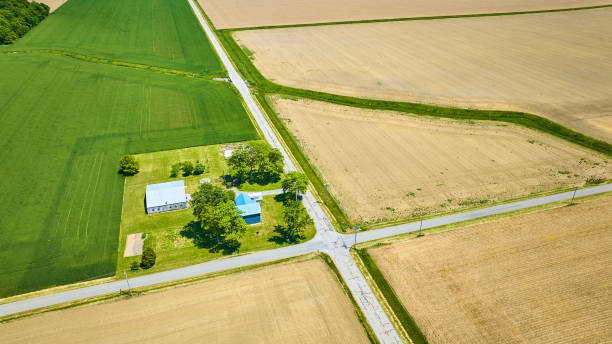 istock Aerial farm house on corner of intersection with green field and three dirt fallow fields 1567309732