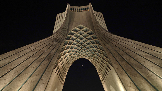 Under the Azadi Tower at Night with a slender moon crescent in the sky in Tehran, Iran
