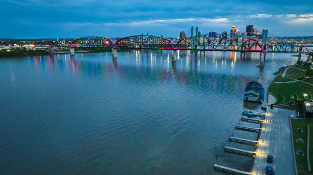 istock Aerial piers in Ohio River water nighttime lights distant arch rainbow light pattern on bridge 1567315826
