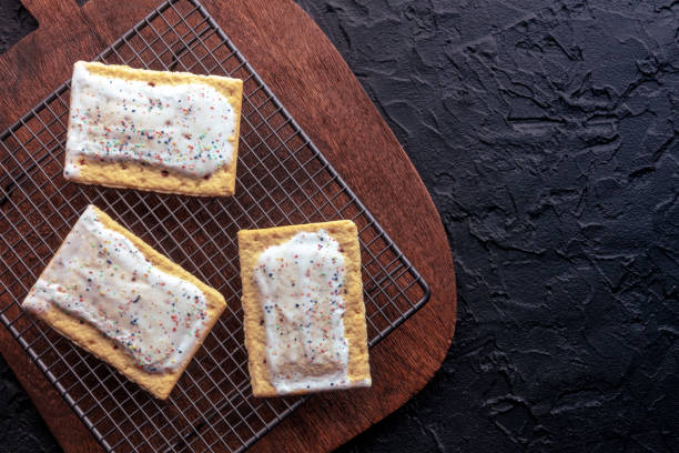 istock Pop tarts on a baking rack. Poptarts with icing on a black background 1567324167