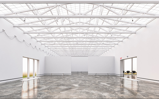 Empty, large gallery/showroom interior with empty white walls, benches and chairs for visitors on both sides on gray cement tile floor. Large ceiling industrial windows with an industrial construction under the roof and illuminated by natural light from large side windows. 3D rendered image.