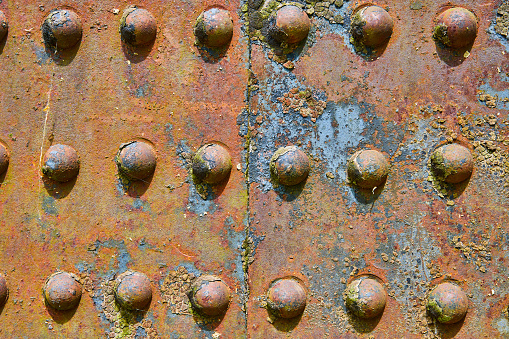Image of Background asset colorful rivets on industry iron metal corroding with flaking yellow rusty decay