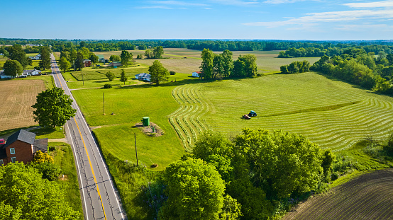 Image of Bright summer day with tractor harvesting field aerial