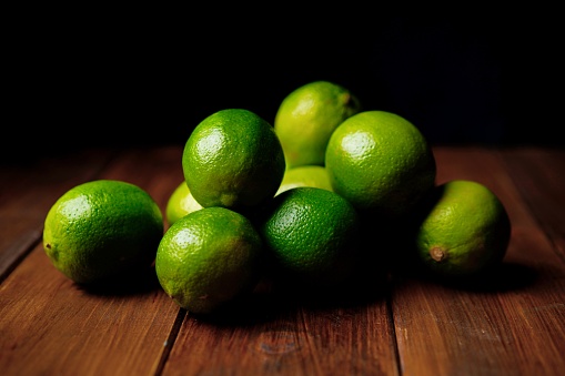 Limes on the wooden table, dark studio shot