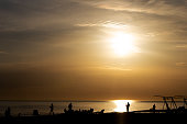 Silhouettes of people resting on the seashore at sunset